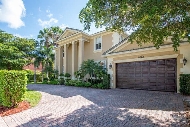 2646 Treanor Ter, Wellington, FL 33414 - greek revival house with stucco siding, decorative driveway, and a garage