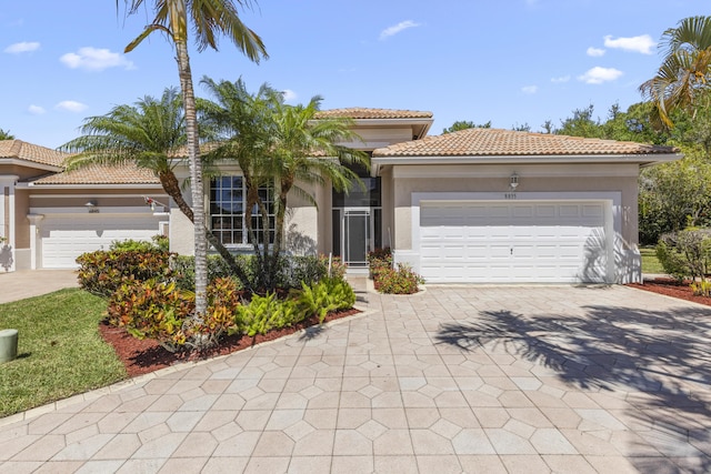mediterranean / spanish home with a tiled roof, stucco siding, an attached garage, and driveway