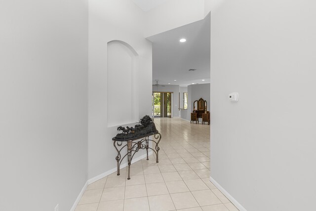 corridor featuring light tile patterned floors, recessed lighting, arched walkways, and baseboards