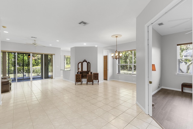 unfurnished living room with recessed lighting, ceiling fan with notable chandelier, visible vents, and baseboards