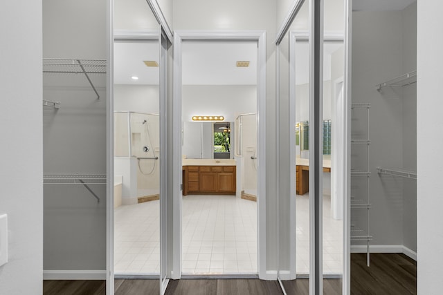 bathroom featuring a spacious closet, visible vents, wood finished floors, and a shower with shower door