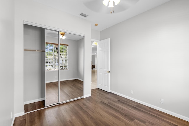 unfurnished bedroom with wood finished floors, visible vents, a closet, and baseboards