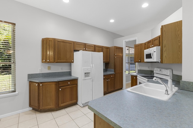 kitchen featuring a sink, white appliances, brown cabinetry, and light tile patterned floors