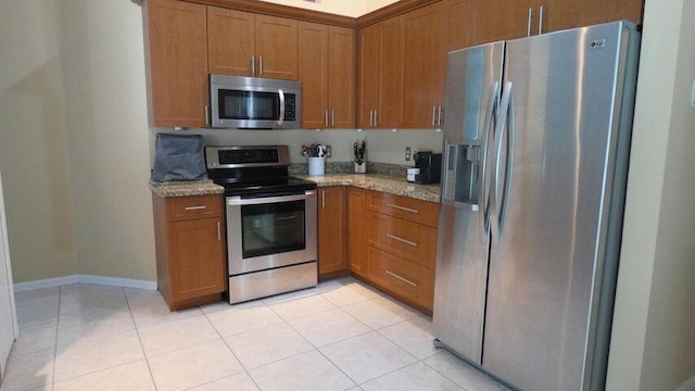 kitchen with light stone counters, brown cabinets, and appliances with stainless steel finishes