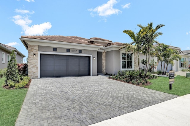 10064 Driftwood Way, Palm Beach Gardens, FL 33412 - view of front of house with decorative driveway, a garage, stucco siding, a front yard, and a tiled roof