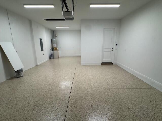 garage featuring baseboards, a garage door opener, and gas water heater
