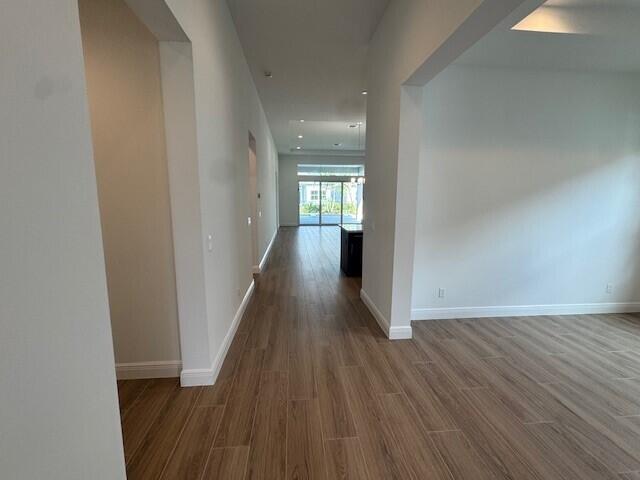 hall with baseboards and wood finished floors