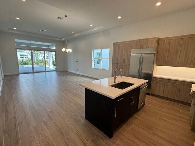 kitchen with appliances with stainless steel finishes, a sink, light countertops, open floor plan, and wood finished floors