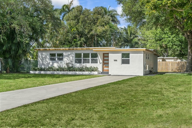 mid-century inspired home featuring stucco siding, driveway, a front lawn, and fence