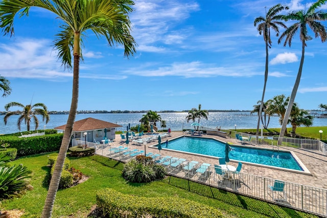 community pool featuring a patio area, a yard, fence, and a water view