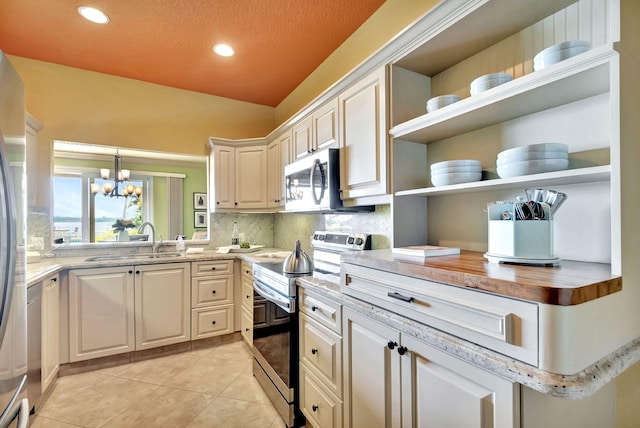 kitchen featuring open shelves, light tile patterned flooring, a sink, appliances with stainless steel finishes, and backsplash