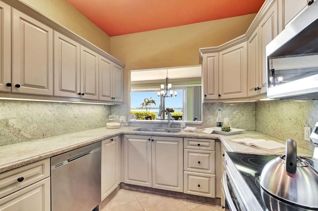 kitchen with backsplash, a chandelier, light tile patterned flooring, stainless steel appliances, and a sink