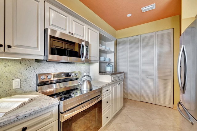kitchen featuring visible vents, backsplash, light tile patterned floors, stainless steel appliances, and white cabinetry