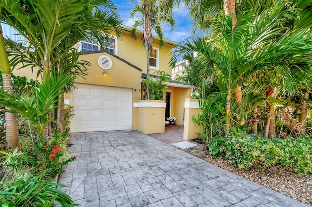 view of front of home with stucco siding, decorative driveway, and a garage