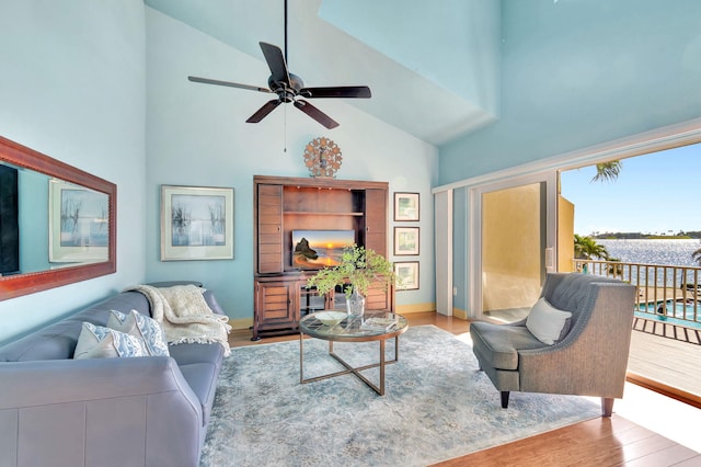 living room with a ceiling fan, wood finished floors, baseboards, and high vaulted ceiling