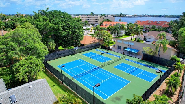 view of sport court featuring fence and a water view