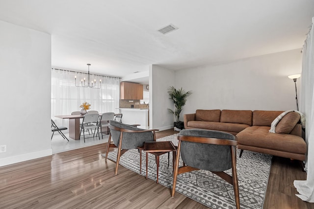 living area featuring light wood finished floors, a notable chandelier, and visible vents