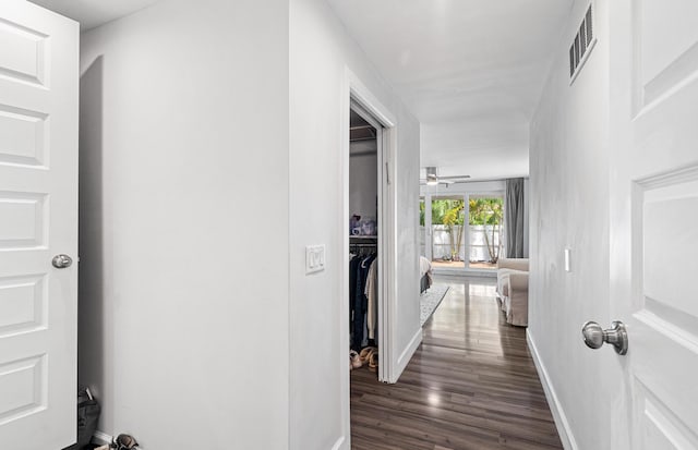 hall featuring visible vents, baseboards, and dark wood finished floors