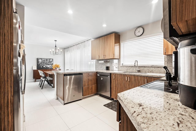 kitchen featuring tasteful backsplash, an inviting chandelier, a peninsula, appliances with stainless steel finishes, and a sink