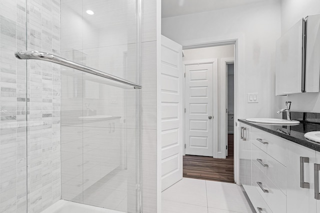 bathroom featuring a shower stall, tile patterned flooring, double vanity, and a sink