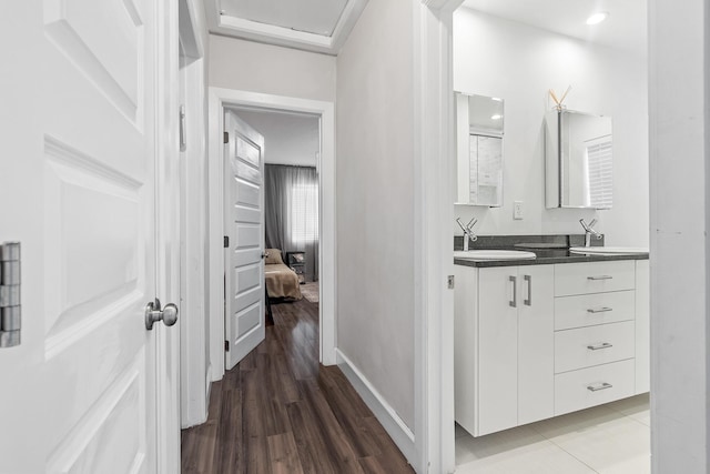 hall featuring light wood-style floors, baseboards, and a sink