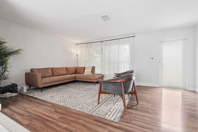 living room with wood finished floors, baseboards, and visible vents
