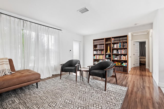 living area with visible vents, baseboards, attic access, and wood finished floors