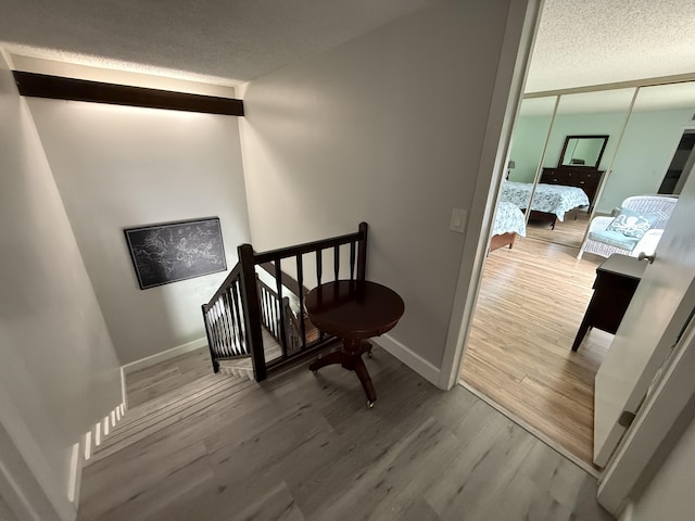 9407 S Ocean Dr Unit 1D, Jensen Beach, FL 34957 - staircase with a textured ceiling, wood finished floors, and baseboards