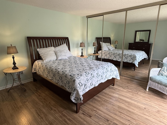 9407 S Ocean Dr Unit 1D, Jensen Beach, FL 34957 - bedroom featuring a closet, wood finished floors, a textured ceiling, and baseboards