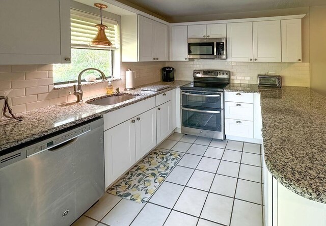 9407 S Ocean Dr Unit 1D, Jensen Beach, FL 34957 - kitchen featuring appliances with stainless steel finishes, a sink, tasteful backsplash, white cabinets, and light tile patterned floors