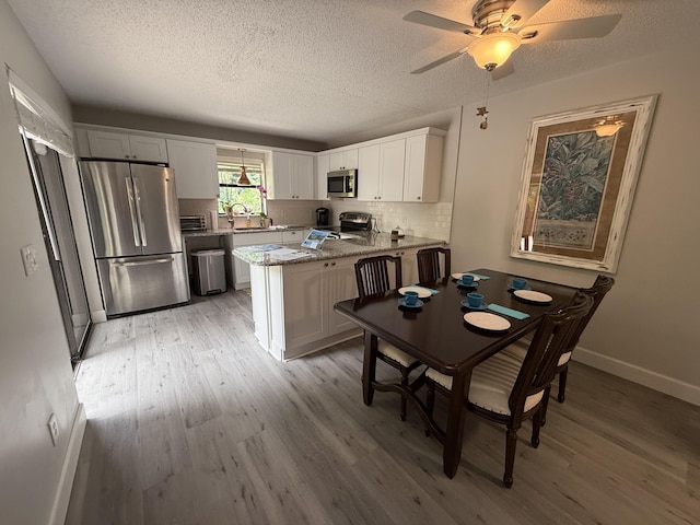9407 S Ocean Dr Unit 1D, Jensen Beach, FL 34957 - dining room featuring light wood finished floors, a textured ceiling, ceiling fan, and baseboards