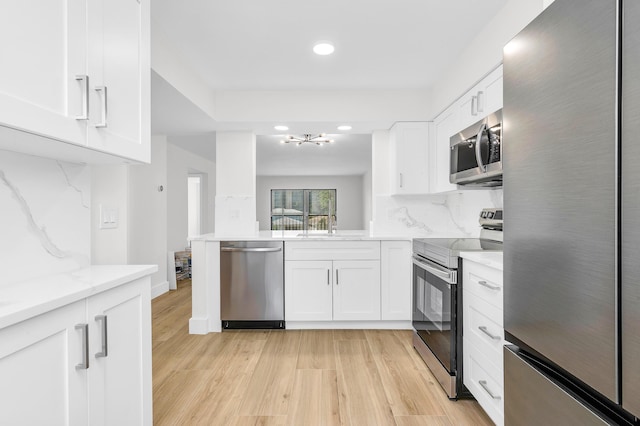kitchen featuring white cabinets, stainless steel appliances, and light wood-type flooring