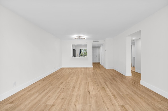 unfurnished living room with visible vents, light wood-type flooring, and baseboards