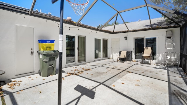 back of property with a patio area, glass enclosure, and stucco siding