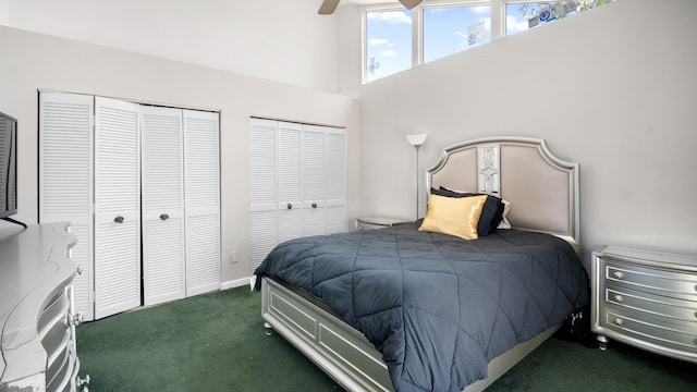 carpeted bedroom featuring a high ceiling, a ceiling fan, and two closets