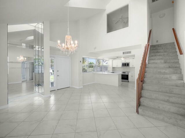3642 SW Sunset Trace Cir, Palm City, FL 34990 - entryway featuring visible vents, a high ceiling, light tile patterned flooring, stairs, and ceiling fan with notable chandelier