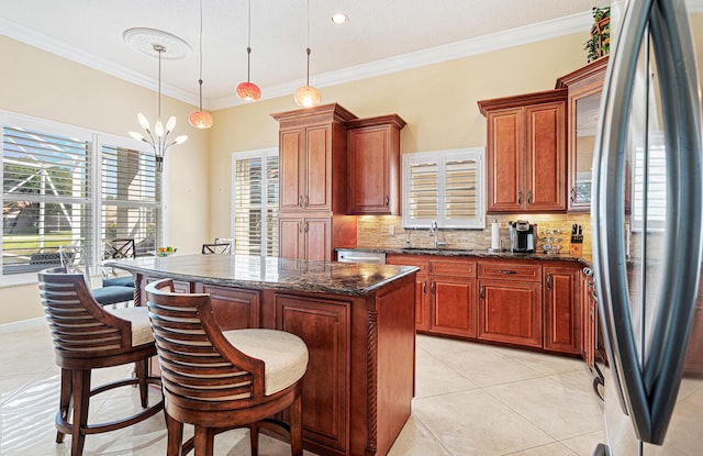 kitchen featuring backsplash, a center island, light tile patterned floors, appliances with stainless steel finishes, and a sink