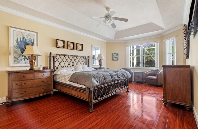 bedroom with dark wood-style flooring, ceiling fan, ornamental molding, a textured ceiling, and a raised ceiling