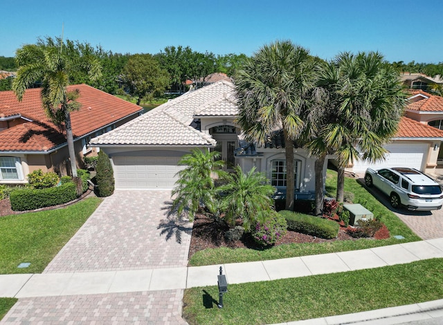 view of front facade featuring decorative driveway, a garage, a front yard, and a tiled roof