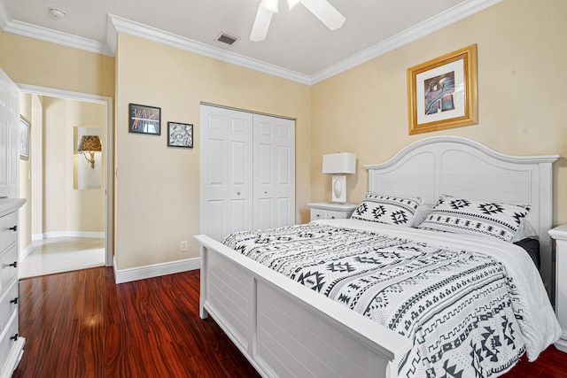 bedroom with visible vents, dark wood-type flooring, a closet, crown molding, and baseboards