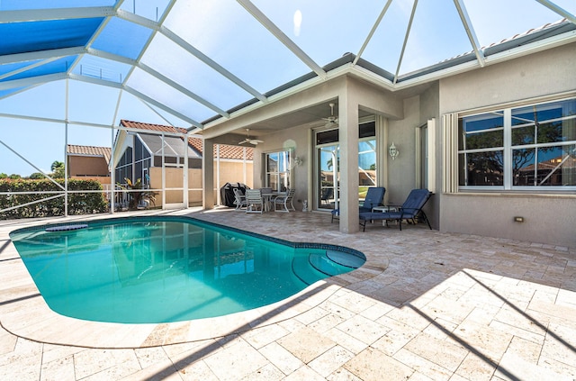 pool featuring glass enclosure, a patio, and a ceiling fan