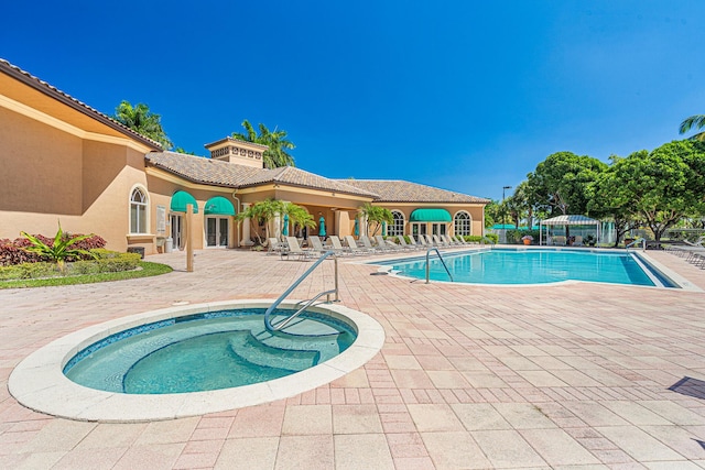 community pool with a community hot tub, a patio, and fence