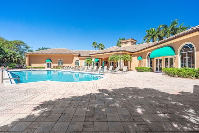 pool with french doors and a patio area