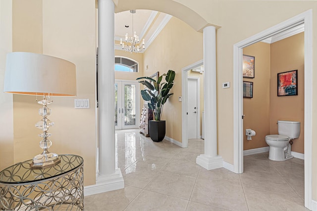 corridor with tile patterned floors, baseboards, decorative columns, a high ceiling, and arched walkways