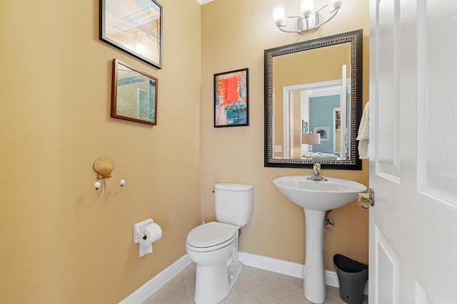 bathroom with tile patterned floors, toilet, baseboards, and a sink