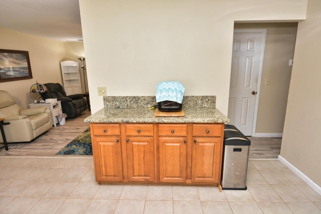 557 SE Seahouse Dr, Port Saint Lucie, FL 34983 - kitchen with light stone countertops, light tile patterned floors, brown cabinets, and open floor plan