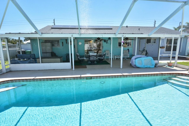 557 SE Seahouse Dr, Port Saint Lucie, FL 34983 - back of house with a patio, roof mounted solar panels, a fenced in pool, and glass enclosure