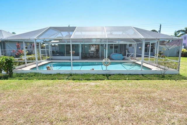 557 SE Seahouse Dr, Port Saint Lucie, FL 34983 - back of house with an outdoor pool, glass enclosure, a patio, and a lawn