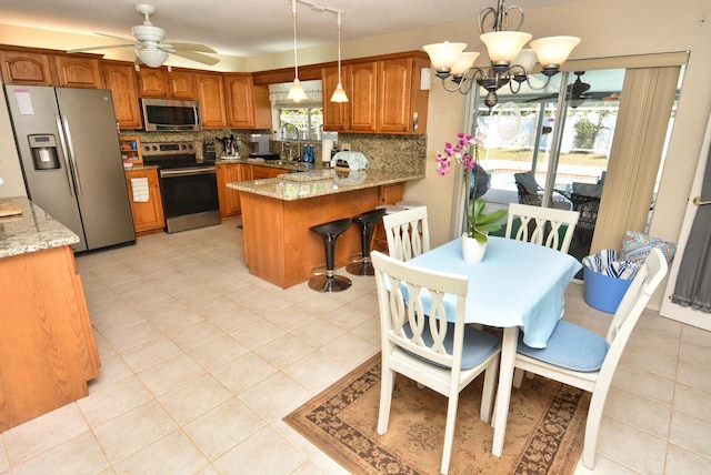 557 SE Seahouse Dr, Port Saint Lucie, FL 34983 - kitchen with appliances with stainless steel finishes, a peninsula, brown cabinets, decorative backsplash, and a sink