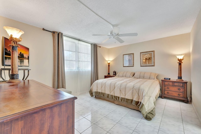 bedroom with a ceiling fan, light tile patterned flooring, and a textured ceiling